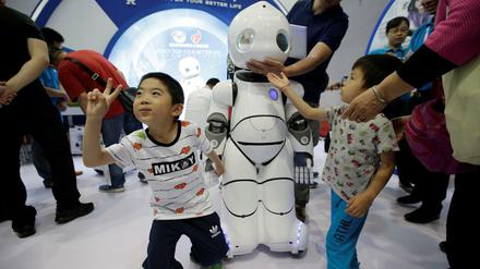 Kinder spielen mit einem Roboter auf der Internationalen High-tech-Expo in Peking. 