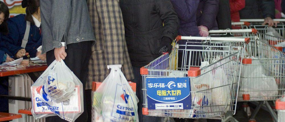 Menschen kaufen in einem Supermarkt in Qingdao, China, ein, dabei benutzen sie Plastiktüten.