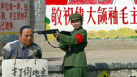 Posieren für die Kulturrevolution: Eine Touristin in Soldatenuniform spielt in einem chinesischen Themenpark mit einer Sträflingsstatue eine Exekution nach. 
