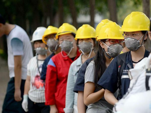 Die Behörden haben den Menschen in der riesigen Industriestadt im Nordosten Chinas empfohlen, Atemmasken zu tragen. Diese Arbeiter sind zum Dienst erschienen. 