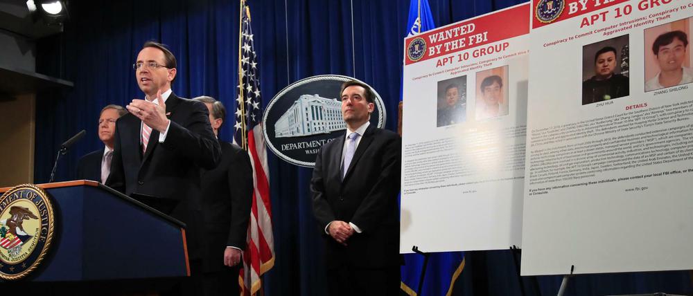 Rod Rosenstein, der stellvertretende Justizminister der USA, gibt mit FBI-Direktor Wray eine Pressekonferenz vor Bildern von zwei Chinesen, gegen die zunächst Anklage erhoben wurde.