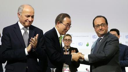 Zwei Präsidenten und ein UN-Generalsekretär. Ban Ki Moon (mitte) freut sich mit Frankreichs Präsidenten Francois Hollande (rechts) über den Abschluss des Pariser Klimavertrags. Links steht der Präsident des Klimagipfels, Außenminister Laurent Fabius. 