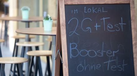 Ein Hinweisschild für die 2G plus Regel steht vor einem Restaurant in der Innenstadt von Stuttgart.