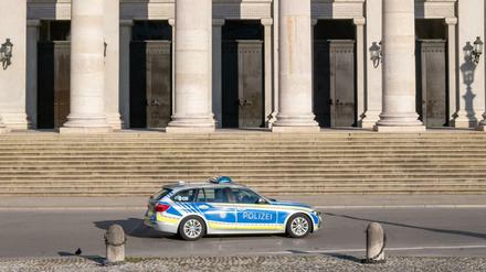 Ein Polizeiauto fährt an der leeren Treppe der bayerischen Staatsoper in München vorbei.