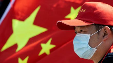 In Wuhan nimmt ein Freiwilliger mit Mundschutz an einer Abschiedszeremonie für Mediziner teil, die der Stadt nach dem Ausbruch des Virus halfen.