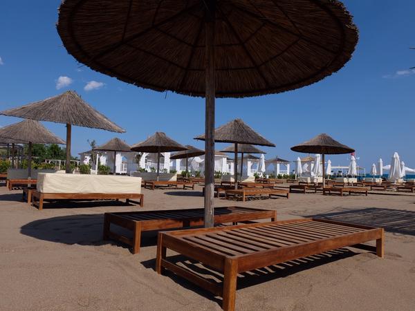 Strandliegen und Sonnenschirme stehen am Strand an einer Hotelanlage in Antalya leer.