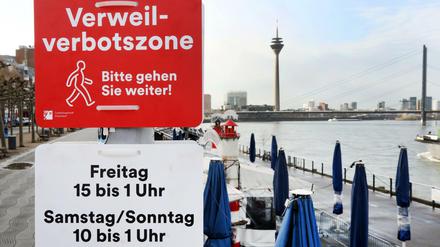 Düsseldorf: Verbotsschilder "Verweilverbotszone - Bitte gehen Sie weiter" und "Freitag 15 bis 1 Uhr - Samstag/Sonntag 10-1 Uhr" an der Rheinpromenade.