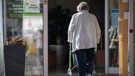 Eine Seniorin betritt mit ihrer Gehhilfe den Eingang eines Senioren-Wohnstifts. Wie weit soll die Isolierung gehen?