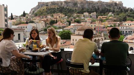 Gäste sitzen in einem Café am Fuße der Akropolis.