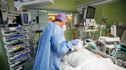 Ein Arzt der Asklepios Klinik in Bayern arbeitet in Schutzkleidung am Bett eines über einen Luftröhrenschnitt beatmeten Corona-Patienten.
