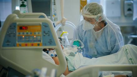 Ein medizinische Mitarbeiterin versorgt einen Intensivpatienten. 