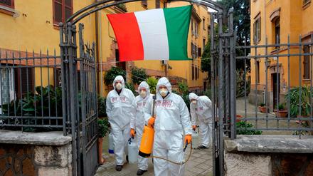 Arbeiter in Schutzkleidung desinfizieren Gehwege in Rom.