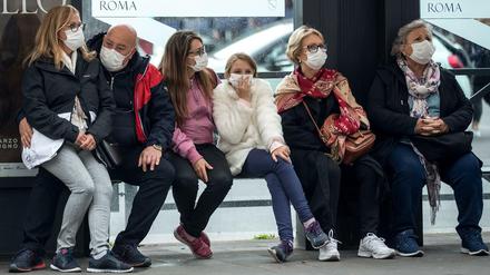 Italien: Reisende mit Mundschutzmasken warten an einer Bushaltestelle. Italien hat die höchste Zahl an nachgewiesenen Covid-19-Toten nach China. 
