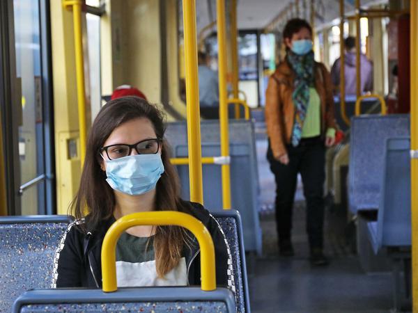 Eine Frau sitzt im April 2020 mit einer Schutzmaske in einer Straßenbahn.