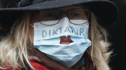 Eine Demonstration trägt eine Maske mit der Aufschrift "Diktatur"