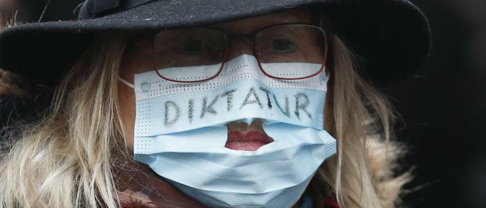 Eine Demonstration trägt eine Maske mit der Aufschrift "Diktatur"