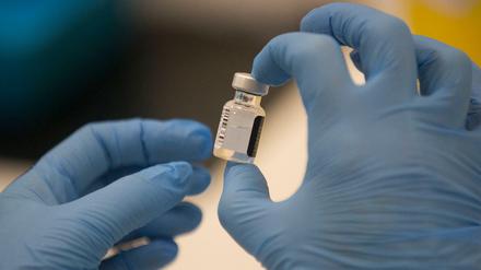 Ein Arbeiter hält eine Ampulle des Pfizer-BioNTech COVID-19-Impfstoffs in der Hand