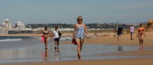 Menschen gehen am Sao-Rafael-Strand in Portugal entlang.
