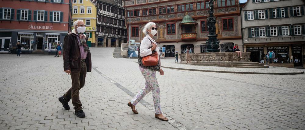 Ein älteres Paar läuft mit Schutzmasken am Tübinger Rathaus vorbei. Auch die Stadt Tübingen plant eine Maskenpflicht.