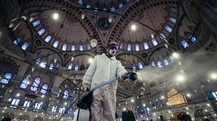 Ein Arbeiter in Schutzkleidung und mit Mundschutz desinfiziert die historische Fatih-Moschee in Istanbul als Vorsichtsmaßnahme gegen das Coronavirus.