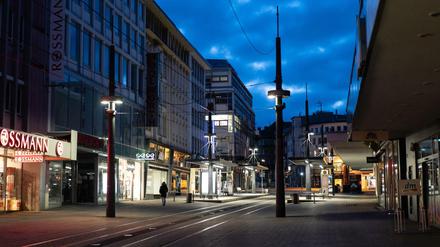 Ein Mann geht in der sogenannten blauen Stunde in Witten an den Geschäften in der ansonsten leeren Fußgängerzone vorbei. 