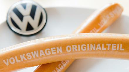 Zwei Würste liegen auf einem Teller mit VW-Logo. 