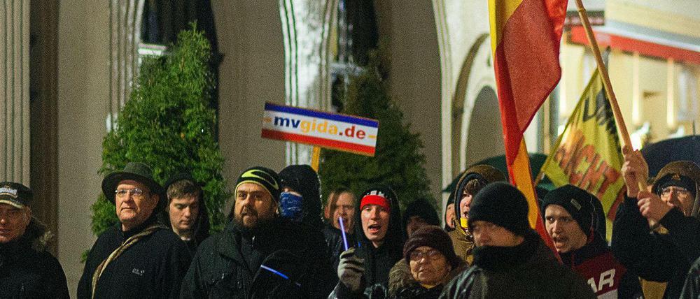 MVGida-Demonstranten halten ein Schild mit der Aufschrift "mvgida.de" hoch - einer Website, die für Nazi-Aussteigerprogramme wirbt