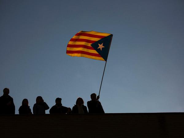 Ein Mann schwenkt am 11.11.2017 auf einem Dach in Barcelona während einer Demonstration die Flagge von Katalonien.