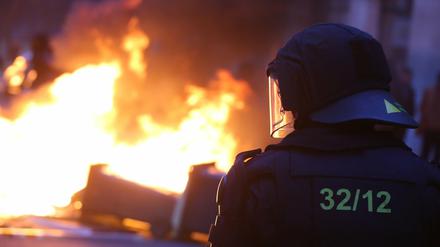 Ein Polizist steht avor einer brennenden Barrikade bei Auseinandersetzungen zwischen linken Gegendemonstranten und der Polizei bei einer Demonstration von Rechtsradikalen.
