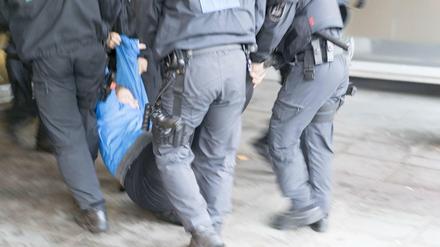 Polizisten schleppen eine Demonstrantin weg.