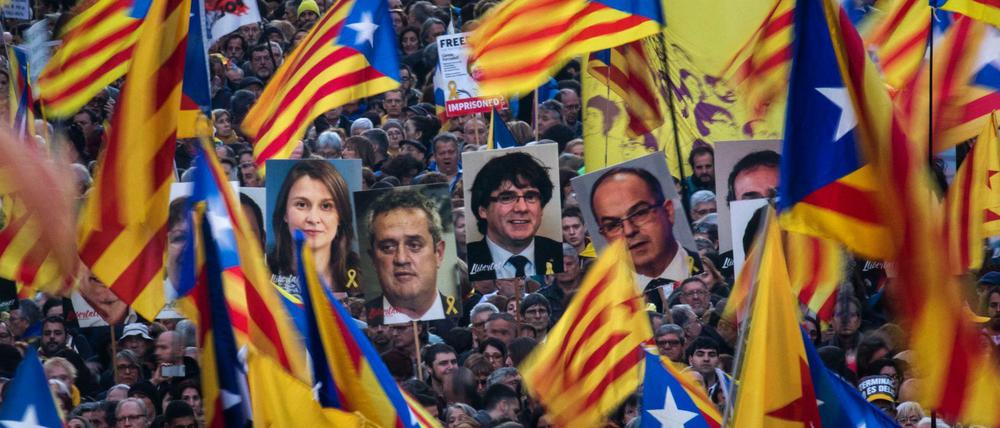 Demonstranten mit Fahnen und Bilder der ehemaligen katalanischen Regierungsmitglieder