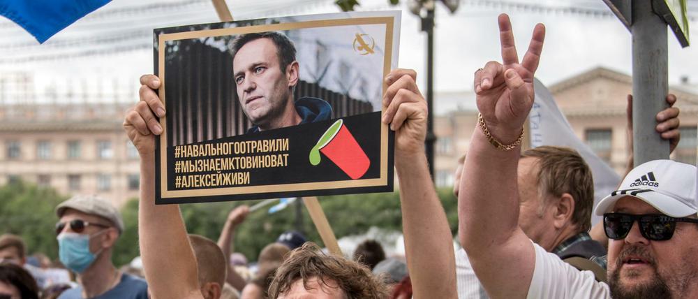 Ein Mann hält bei einer Demonstration in Russland ein Foto von Nawalny, auf dem zu lesen ist: "Nawalny wurde vergiftet, wir wissen, wer schuld ist, Alexej du musst leben". 