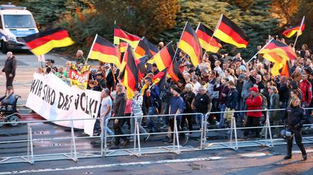 Teilnehmer einer Demonstration der rechtspopulistischen Bewegung Pro Chemnitz ziehen hinter Absperrgittern durch die Stadt.
