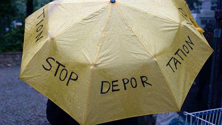 Regenschirm mit Protest-Slogan gegen Abschiebung von Flüchtlingen.