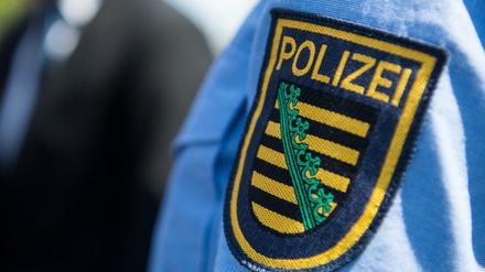 Das Logo der sächsischen Polizei ist an einem Polizeiuniform angebracht.