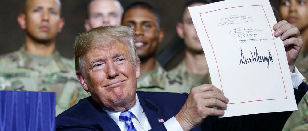 US-Präsident Donald Trump zeigt in der Militärbasis Fort Drum das frisch unterzeichnete Ausgabengesetz.
