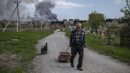 Ein Mann in Mariupol, im Hintergrund Rauchwolken über dem umkämpften Stahlwerk