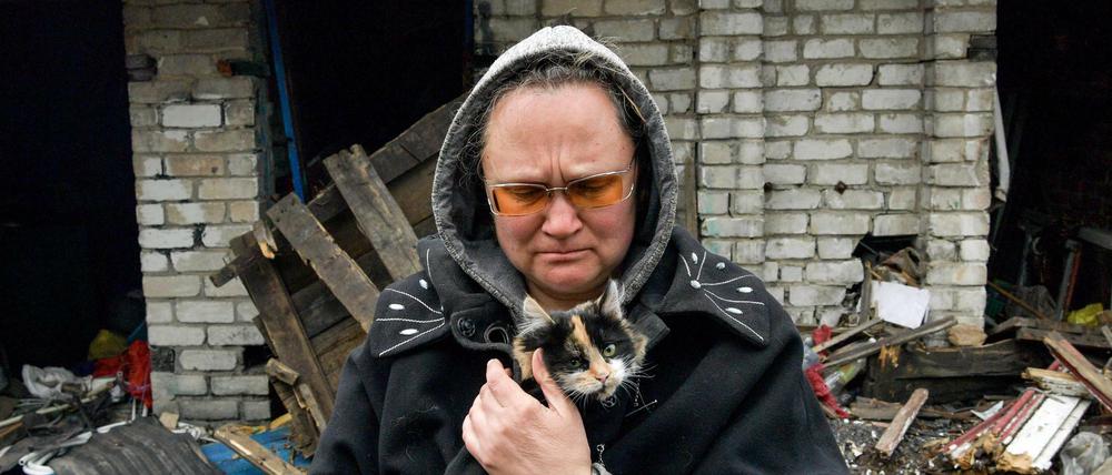 Eine Frau mit ihrer Katze in einem zerstörten Dorf in der Region Luhansk