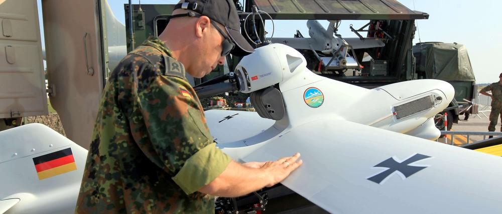 Ein Soldat der Bundeswehr steht neben einer Drohne vom Typ "Luna". 