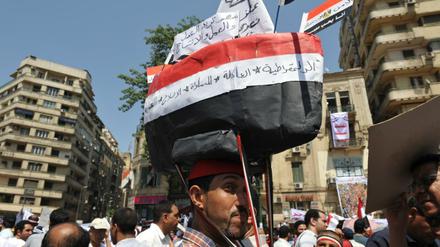 Dieser Demonstrant hat sich ein Schiff aus Pappe in den Farben Ägyptens auf den Kopf geschnallt. „Wir müssen wieder auf den richtigen Kurs“, sagt er. 