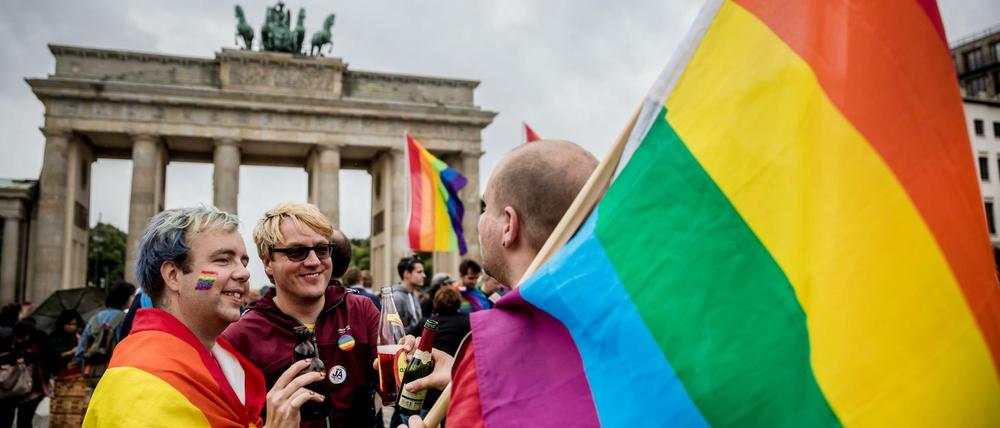 Männer mit Regenbogenflaggen feiern vor dem Brandenburger Tor in Berlin.