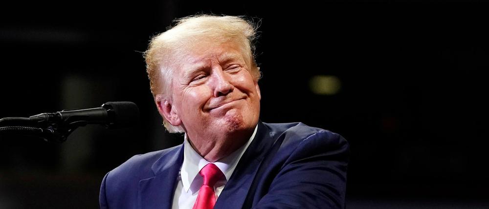 Donald Trump lächelt bei einer Pressekonferenz in Richtung der Journalisten