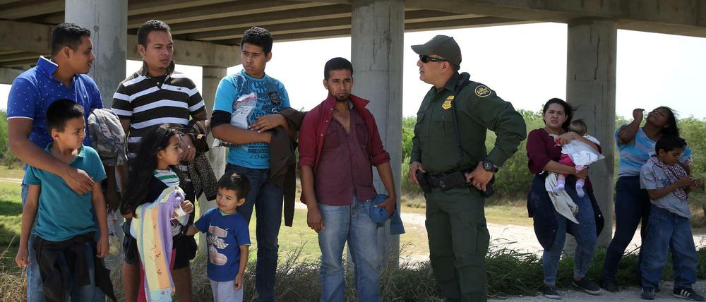 Migranten mit Kindern sprechen mit einem Grenzbeamten.