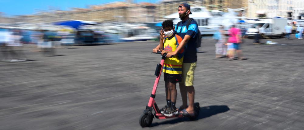 (FILES) In this file photo taken on August 26, 2020 youth wearing face masks ride a scooter in the old harbour of Marseille, southestern France. (Photo by Christophe SIMON / AFP)
