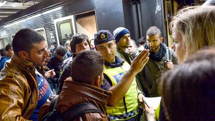 Flüchtlinge werden im Bahnhof in Stockholm von einem Polizisten weitergeleitet.