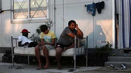 Flüchtlinge sitzen vor einem Wohncontainer in Athen.