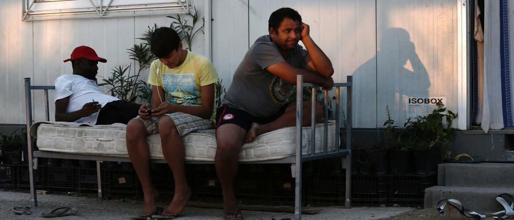 Flüchtlinge sitzen vor einem Wohncontainer in Athen.