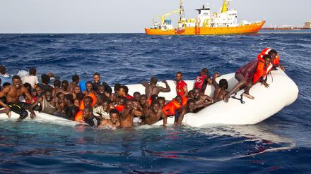 Flüchtlinge sitzen auf dem Mittelmeer in einem sinkenden Schlauchboot 
