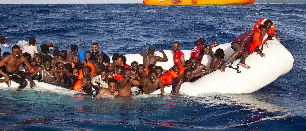 Flüchtlinge sitzen auf dem Mittelmeer in einem sinkenden Schlauchboot 