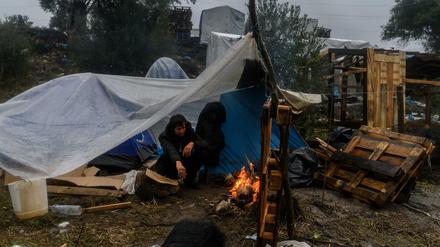 Flüchtling auf Moria. Ein Migrant versucht sich an einem kleinen Feuer in einem provisorischen Lager neben dem Camp Moria auf der griechischen Insel Lesbos aufzuwärmen. 